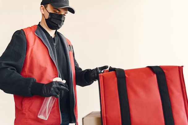 Delivery man spray sanitizing on a box - Foto, Imagem