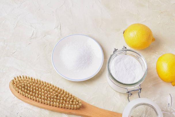 citric acid, soda, lemons and a wooden brush on a light background for eco cleaning, natural and non-toxic detergents, zero waste lifestyle concept - 写真・画像