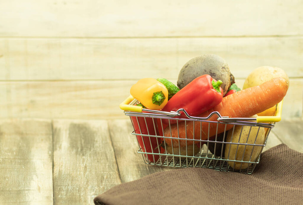 Friss és egészséges zöldségek a kosárban. Zöldségek egy vas kosárban, mint egy háttér szöveges hely. Friss zöldségek az asztalon és a kosárban. Zöldségek vegetáriánusoknak. Egészséges petíció - Fotó, kép