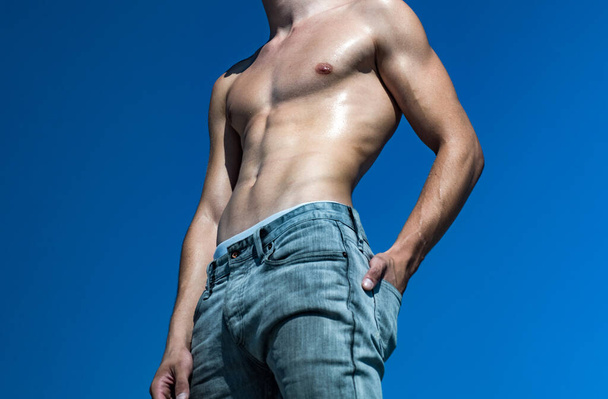 М'язистий молодий хлопець з сексуальним торсом на блакитному небі
. - Фото, зображення