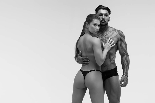 Bianco e nero tatuato senza maglietta uomo e seducente donna in topless guardando altrove - Foto, immagini