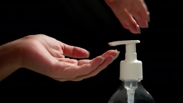 Ženské ruce stiskněte antiseptický dávkovač a stiskněte gel zblízka, tmavé pozadí - Záběry, video