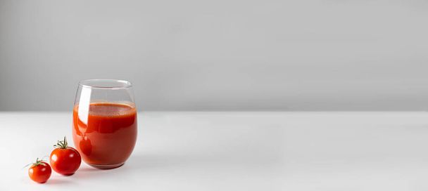 Bio-Tomatensaft im Glas mit frischen Tomaten auf weißem Brett und grauer Wand. Gesundes Essen. Horizontales Banner mit Kopierraum - Foto, Bild