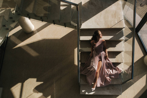 Top view of elegant woman in gorgeous dress lies on the stairs in luxury restaurant - 写真・画像