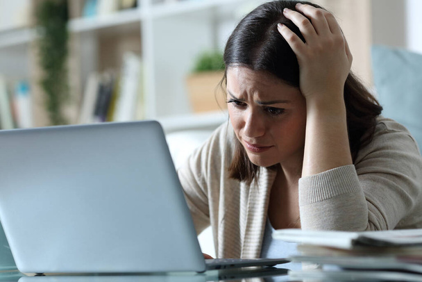 Sad woman complaining checking bad news on email email on a laptop at home - Фото, изображение