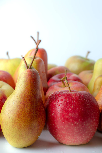 Peras maduras, jugosas y manzanas de cerca se colocan en filas sobre un fondo blanco. - Foto, Imagen