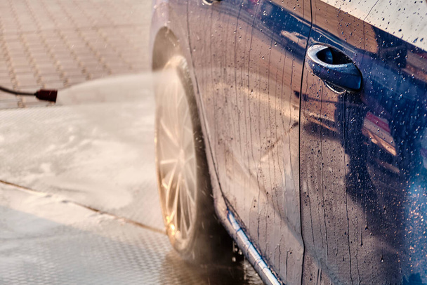 Close up a wheel washing under high water pressure. Manual car washing self service concept.  - 写真・画像