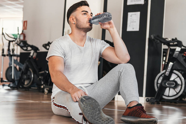 boy resting while hydrating in gym - Photo, Image