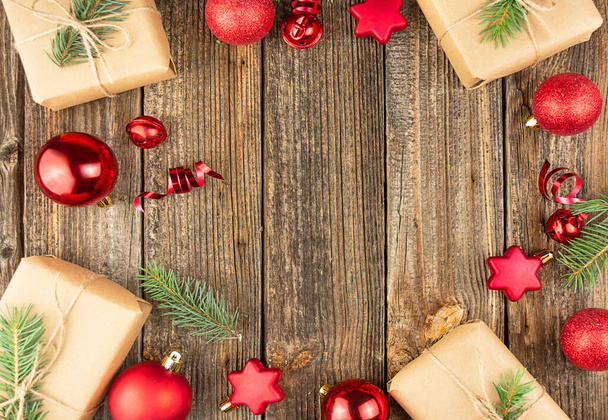 Karácsonyi keret piros játékokkal, fenyőágakkal és ajándékdobozokkal egy fa asztalon. Karácsonyi üdvözlőlap. Baner vagyok. Lapos réteg. Felülnézet másolási hellyel. - Fotó, kép