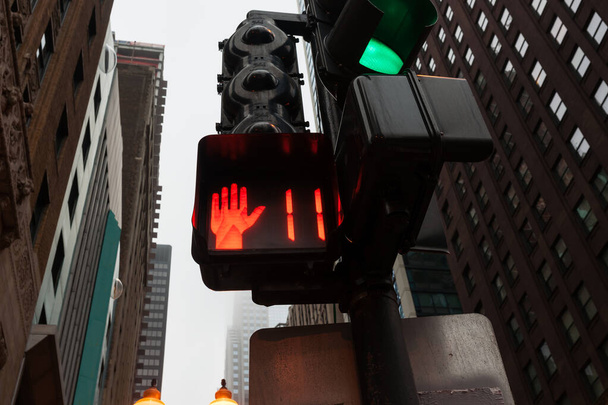Signalleuchten an einem Fußgängerüberweg tief in der Stadt Chicago aus niedrigem Winkel, umgeben von hohen Gebäuden - Foto, Bild