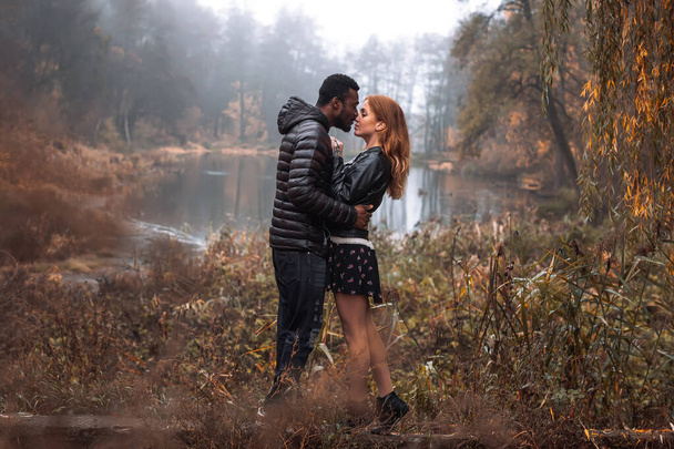 Interracial couple posing in autumn leaves background, black man and white redhead woman - Φωτογραφία, εικόνα