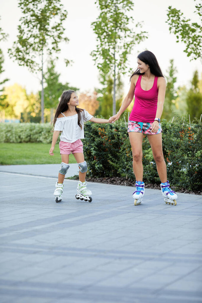 Young mother and her little daughter rollerskating - Φωτογραφία, εικόνα