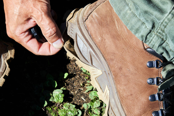 die Hand eines Wanderers, der die Sohle eines Wanderstiefels zeigt, der sich vom intensiven Gehen abgeschält hat - Foto, Bild