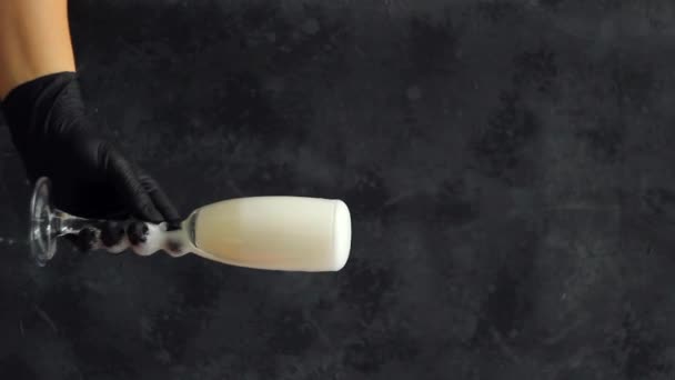 Een hand in een zwarte medische handschoen met een glas champagne. verticale oriëntatie - Video