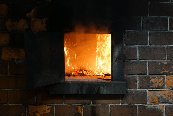 Ревущий огонь ярко горит в камине, с пеплом и красными углями. - Фото, изображение