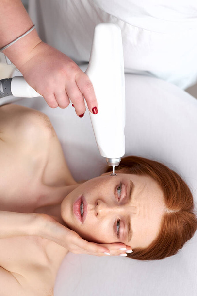 woman scared by electric massage on face - Photo, Image