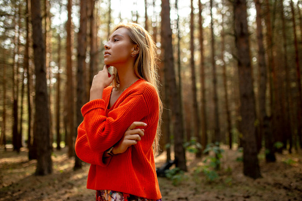 秋の公園でオレンジ色のセーターを着た若い女性のプロフィール写真. - 写真・画像
