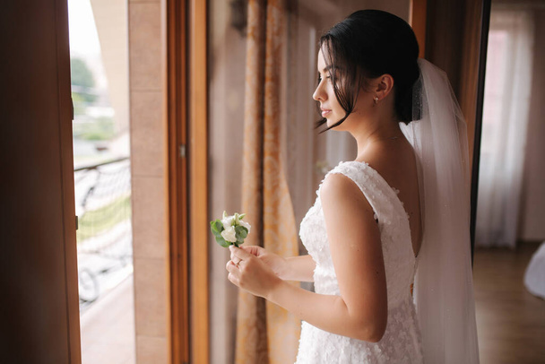 Eerste blik van bruidegom en bruid thuis. Tedere bruid Sta bij het raam en wacht op bruidegom - Foto, afbeelding