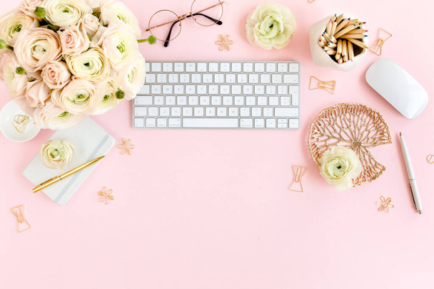 Stylized, pink womens home office desk. Workspace with computer, bouquet ranunculus and roses, clipboard on pink background. Flat lay. Top view. - Foto, imagen