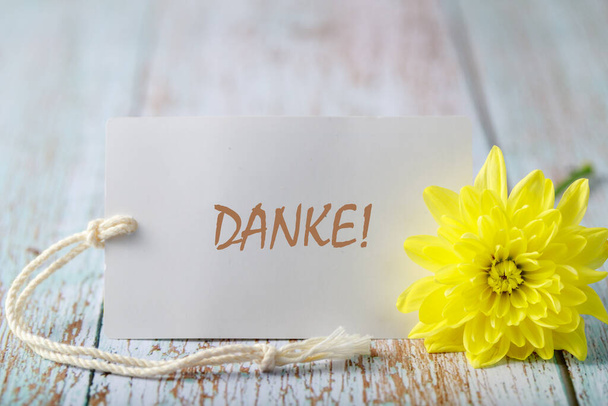 Flor de crisantemo con texto alemán Danke (inglés Gracias) tarjeta sobre fondo de madera - Foto, Imagen