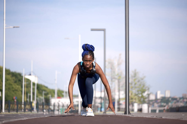 athletic african american girl stands at the start, about to run - 写真・画像