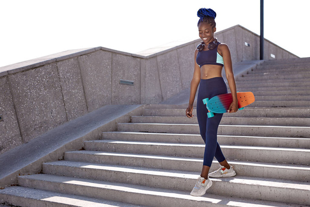 happy african woman hold skateboard in hands and walk - Фото, зображення