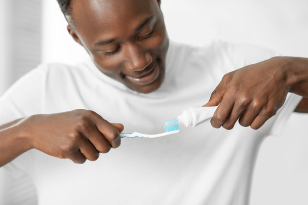 African American Man Zastosowanie Pasta do zębów Czyszczenie zębów w łazience - Zdjęcie, obraz