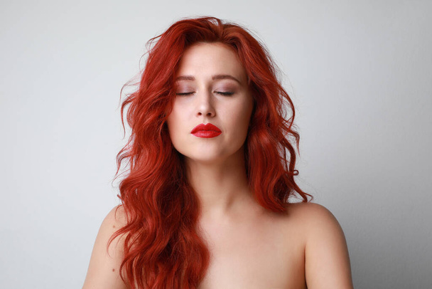 Headshot of sensual woman with closed eyes and beautiful long red hair posing over white background. Space for text. - Photo, image