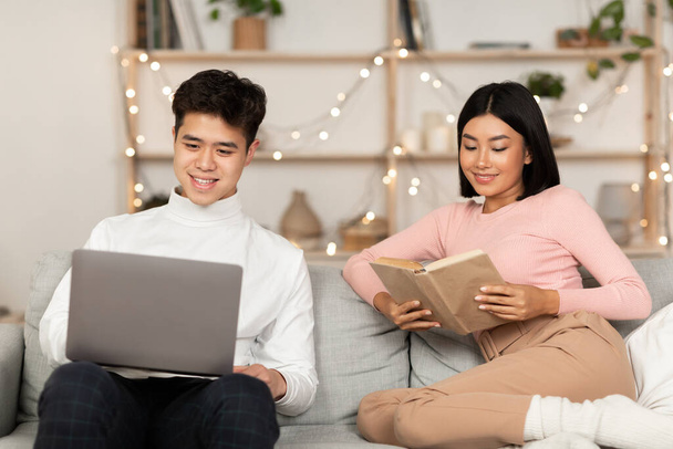 Азиатская семейная пара расслабляется с ноутбуком и забронировать дома - Фото, изображение