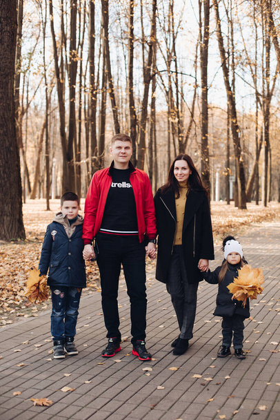 Famille caucasienne va faire une promenade dans le parc d'automne avec deux enfants - Photo, image