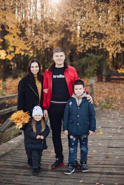 Onnellinen perhe äiti, isä ja kaksi lasta poseeraa yhdessä ulkona - Valokuva, kuva
