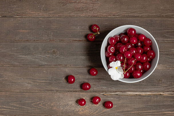 Fresh cherries in a bowl on vintage wooden background with copy space - Photo, Image