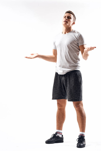 Athletic man on a light background in full growth and jogging charging shorts sneakers t-shirt - Foto, imagen