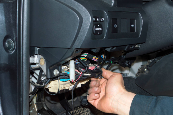 Electrician puts wiring under the dashboard of the car in the garage - Photo, Image