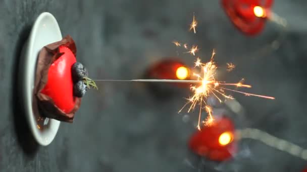 Dolce rosso festivo con sparkler in fiamme su sfondo scuro. orientamento verticale dello schermo. - Filmati, video