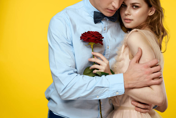 Enamored άνδρας και γυναίκα με κόκκινο τριαντάφυλλο σε κίτρινο φόντο περικοπή προβολή close-up ειδύλλιο - Φωτογραφία, εικόνα