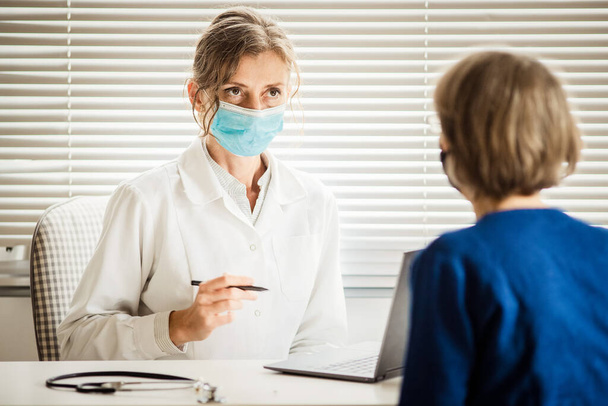 medico donna che consulta un paziente che indossa una maschera medica - Foto, immagini