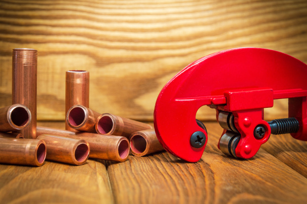 Медные трубы и красные трубы с соединителями для ремонта сантехники на старинных деревянных досках крупным планом - Фото, изображение
