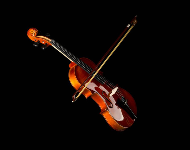 Brown wooden fiddle or violin, classic musical instrument, with bow isolated over black background, selective focus - Zdjęcie, obraz