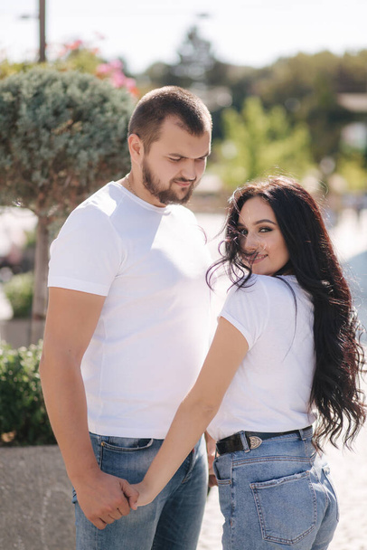 Stylish couple in denim and white t-shirts stand in centre of the city. Late summer concept - Zdjęcie, obraz