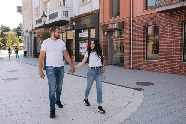 Щаслива пара гуляє в центрі міста. Красивий чоловік і приваблива жінка в білих сорочках
 - Фото, зображення