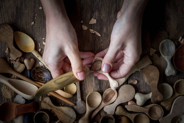Handgefertigte Kochutensilien aus Holz, Frauenhände schnitzen einen Kochlöffel mit Stockmesser, selektiver Fokus - Foto, Bild