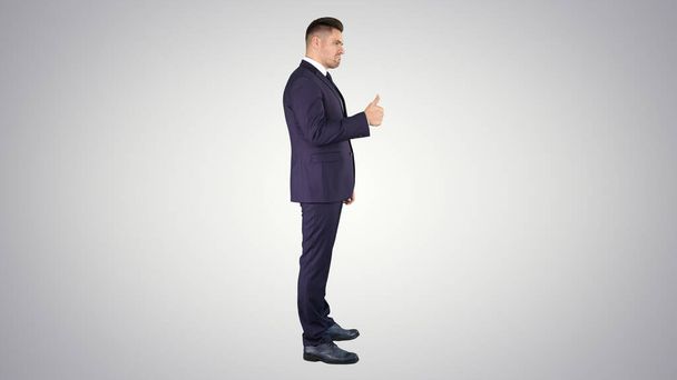 Businessman showing thumbs up on gradient background. - Foto, Imagen