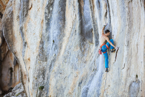 Kaukázusi fiatalember mászás kihívást jelentő útvonal a sziklán - Fotó, kép