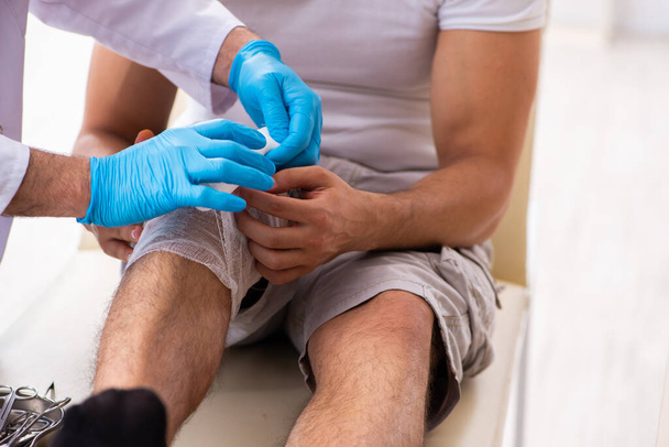 Leg injured man visiting old doctor in first aid concept - Φωτογραφία, εικόνα