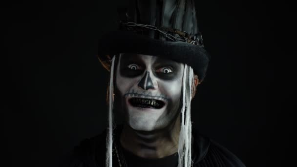 Sinistere man met schedel make-up die zijn mond opent en vieze zwarte tanden laat zien. Halloweenskelet - Video