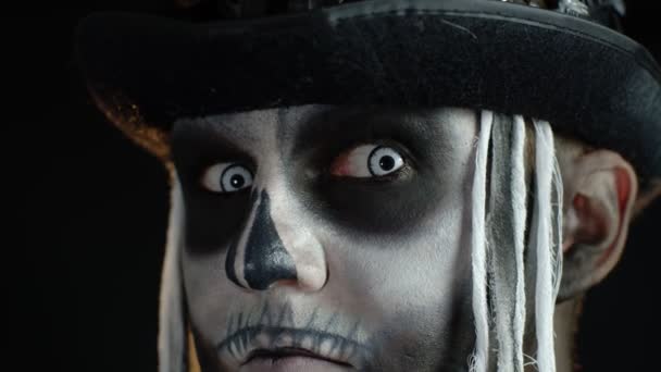 Close-up shot of creepy man in skeleton Halloween makeup opening eyes and looking spooky at camera - Footage, Video