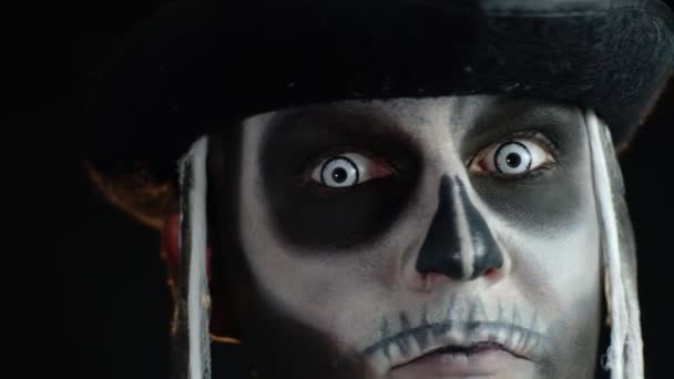 Hombre aterrador en disfraz de cosplay esqueleto de Halloween mirando asustadizo a la cámara. Movimiento lento - Metraje, vídeo