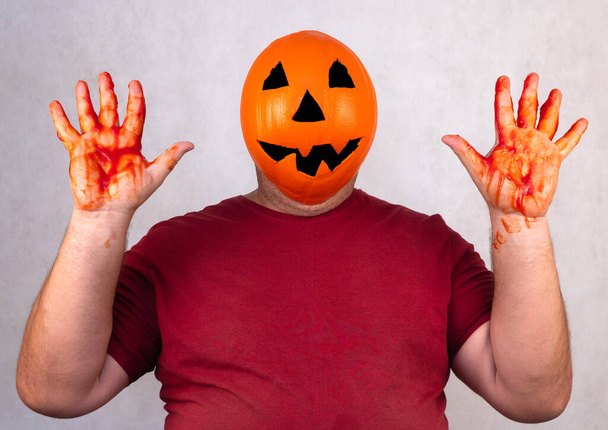 man in a Halloween mask on a white background. person with orange pumpkin evil mask. Jack lantern mask from a basketball. holiday concept - Photo, Image