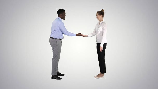African man and caucasian woman giving low five on gradient back - Zdjęcie, obraz